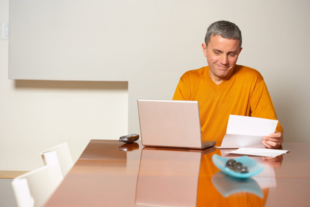 Man at home with laptop reading letter - residential shredding