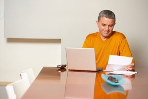 Man at home with laptop reading letter