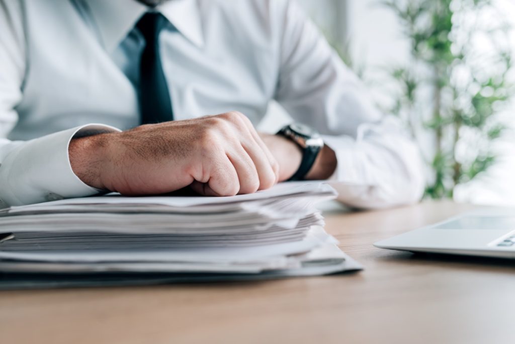 A professional man at a desk, engrossed in paperwork, wearing a white shirt and tie.