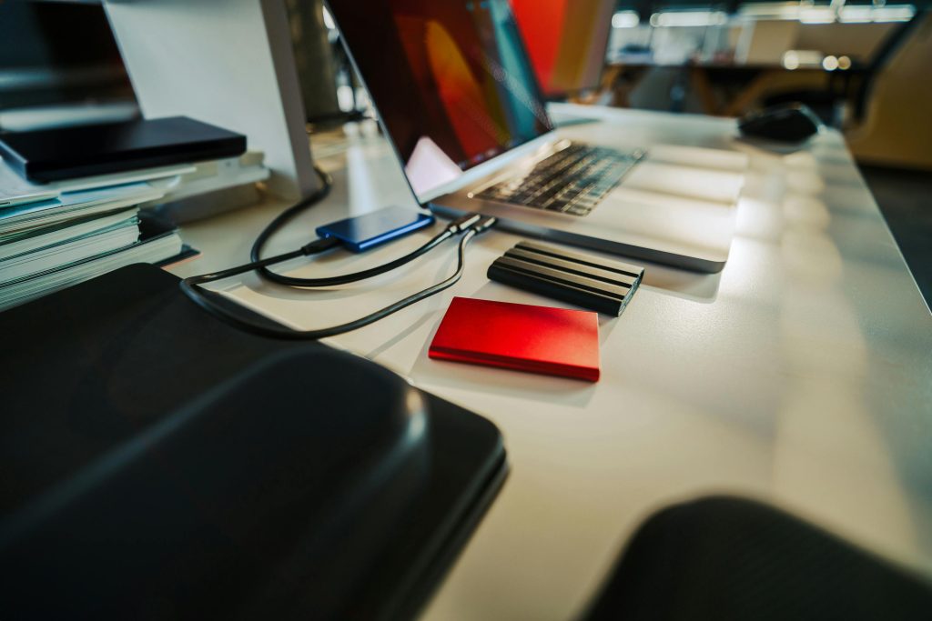 A desk with a laptop and external harddrives.